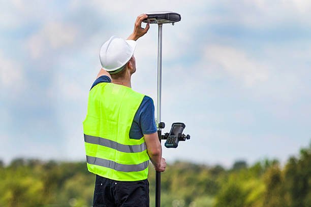 Surveyor using GPS surveying equipment during a topographical survey in Essex.