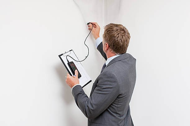Surveyor using a moisture meter during a professional damp survey in Essex.